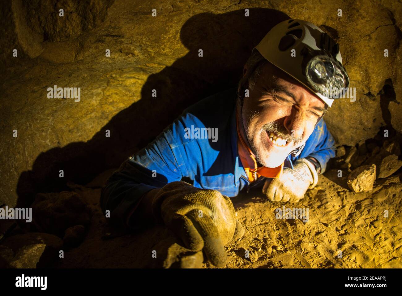 Speleology, man squeezes through crevices, almost no way through Stock Photo