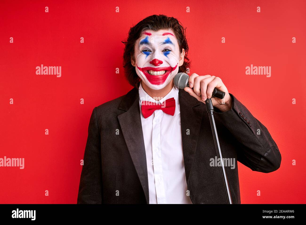 magician with microphone isolated on red background, joyful magic trick