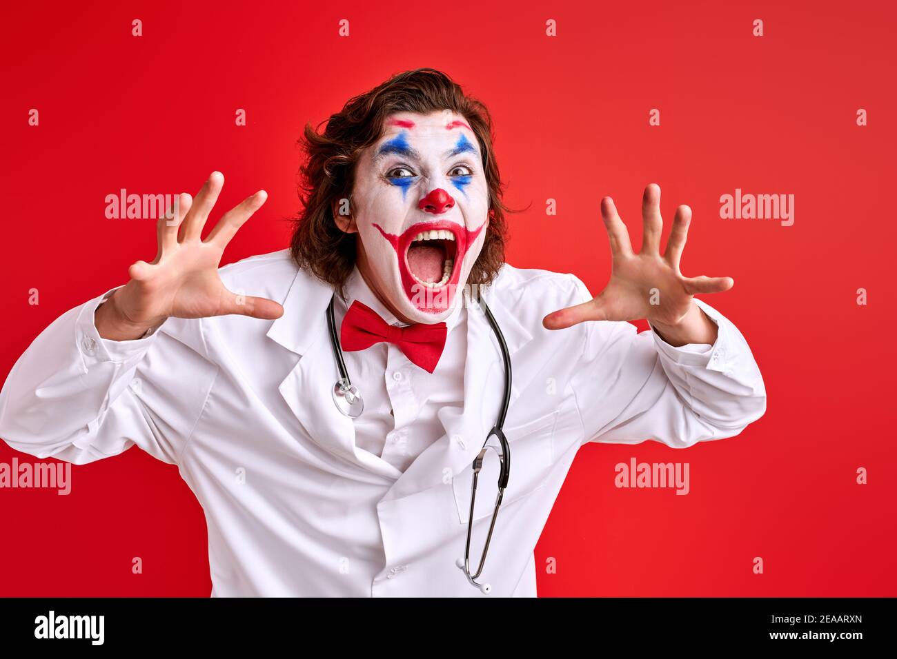 deterrent clown male screaming at camera with spread arms. wearing