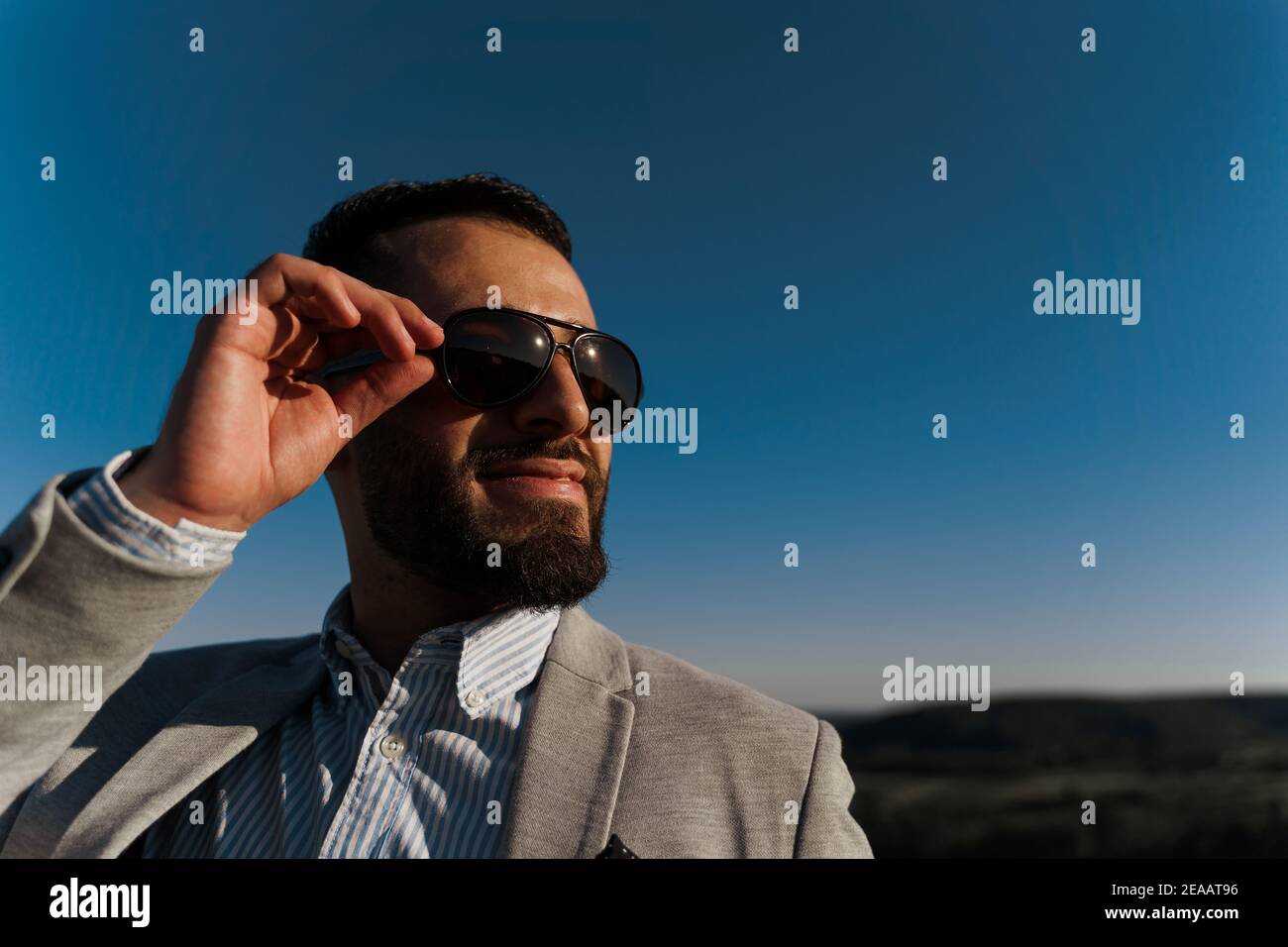 Handsome bearded arabian man in sunglasses on the blue sky background