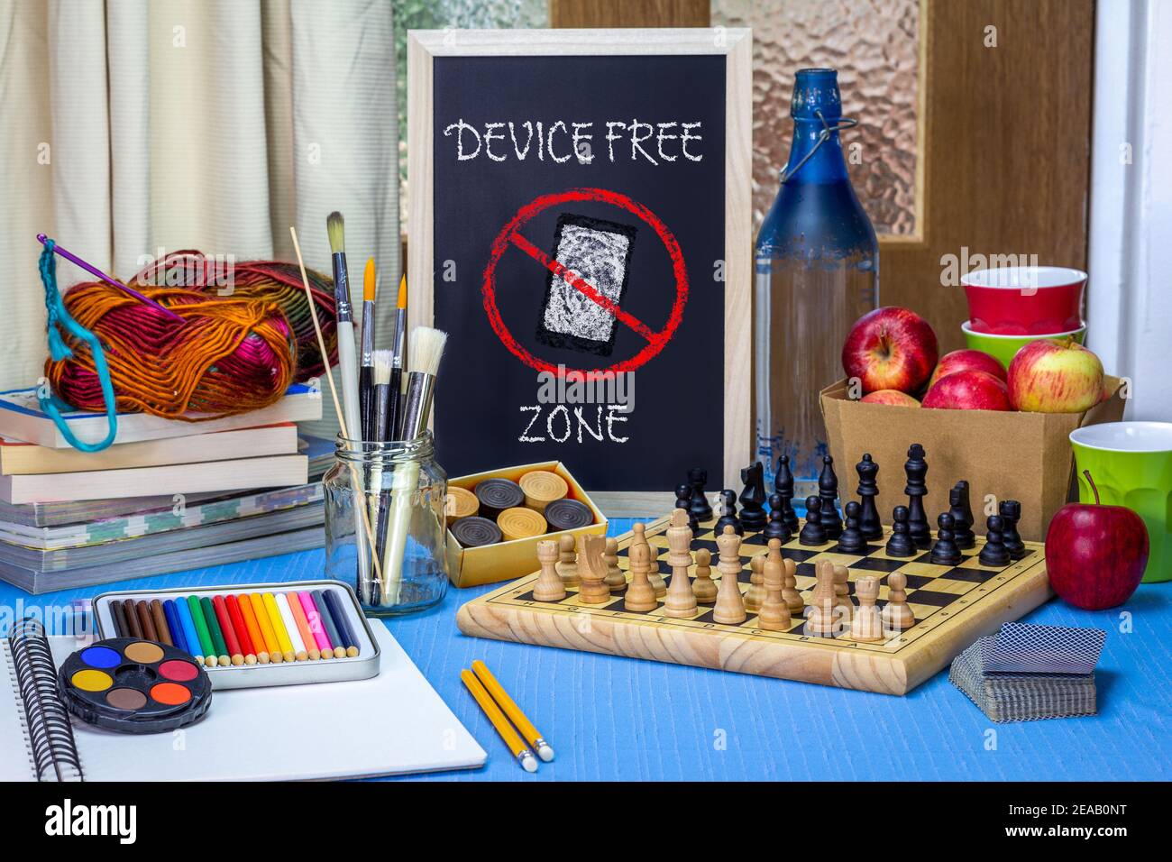 Device Free Zone chalk board on table with games, art materials, books and chess board. Encouraging digital down time to reconnect with people. Stock Photo