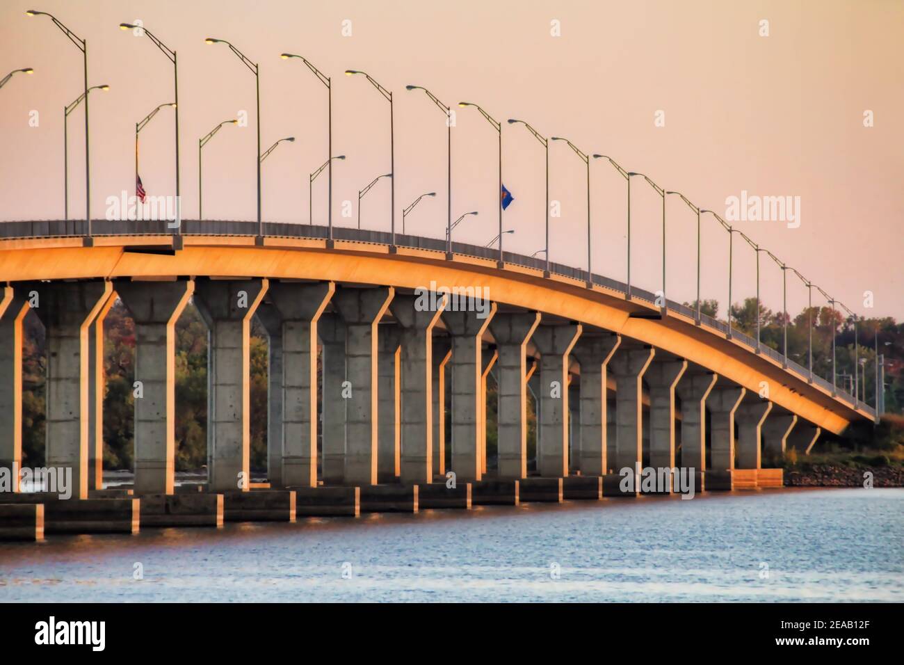 Looking diagonally at the Sailboat Bridge, a bridge that crosses Grand Lake into Grove Oklahoma, this view from the water at sunset shows its height. Stock Photo