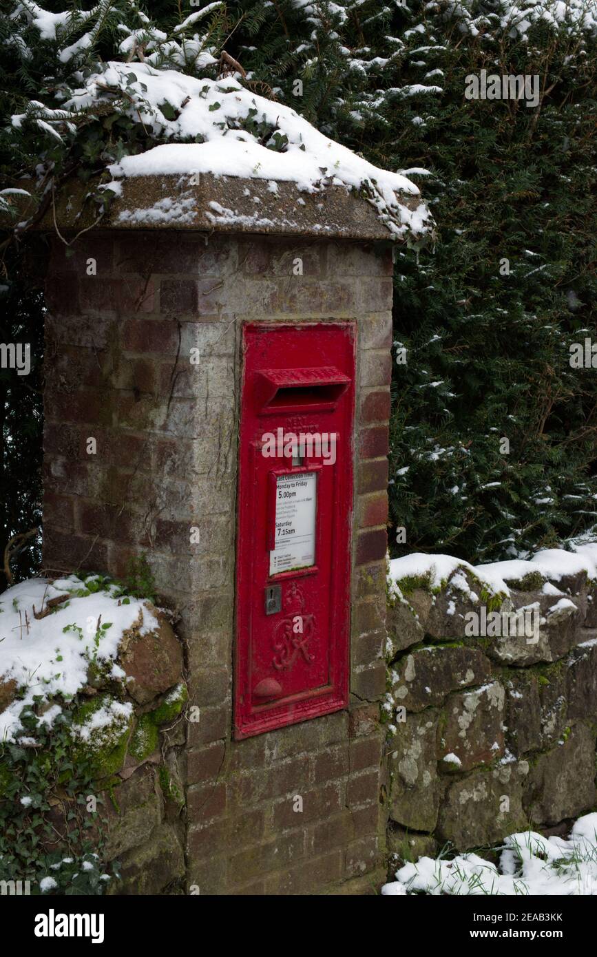 A post box mounted in a wall in a village with snow. during winter. Stock Photo