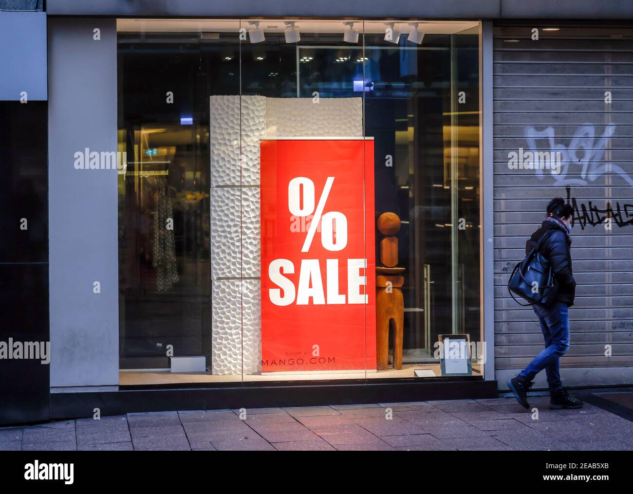 Essen, Ruhr area, North Rhine-Westphalia, Germany - shop window of a fashion store at Christmas time with special offers, passer-by with protective mask in downtown Essen in times of the corona crisis during the second lockdown. Stock Photo