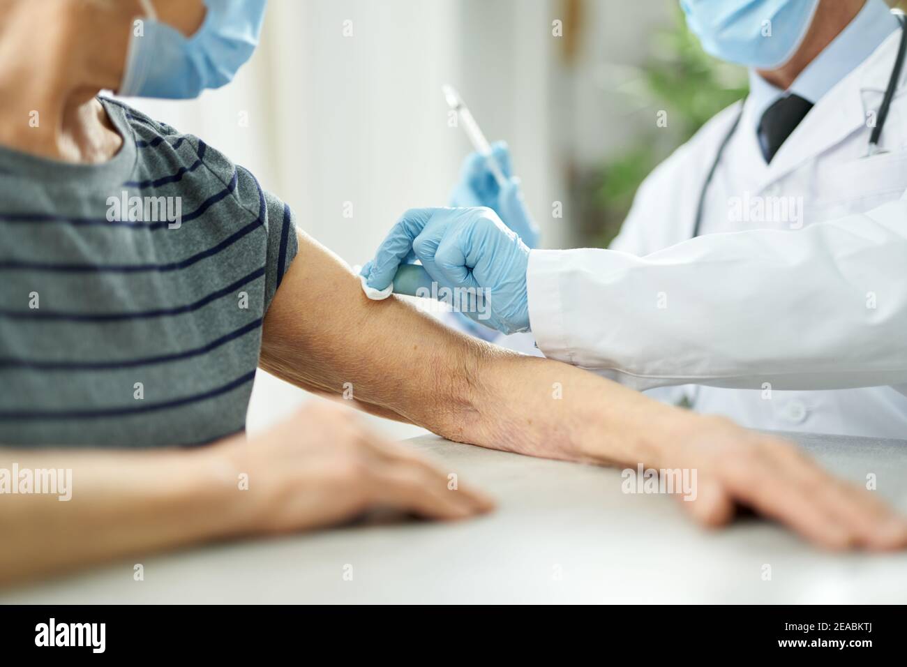 Doctor cleaning patient arm with alcohol swab before injection Stock