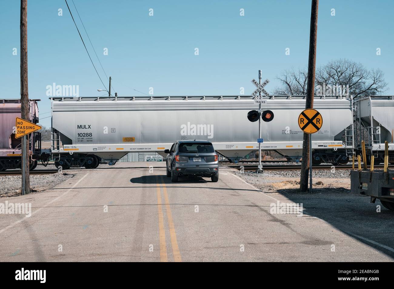 Car traffic stopped at guarded railroad crossing as a freight train passes in Montgomery Alabama, USA. Stock Photo