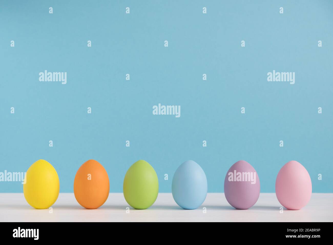 Colorful eggs on light blue background. Happy Easter background. Minimal Easter. Rainbow color Stock Photo