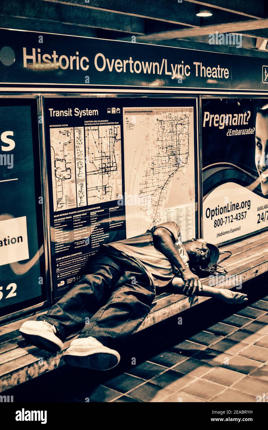 A man sleeps on a bench in the Historic Overtown Metrorail Station in downtown Miami, Florida. Stock Photo