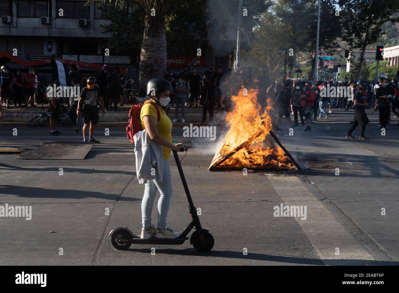 Santiago, Metropolitana, Chile. 8th Feb, 2021. A woman rides an electric  scooter past a barricade during a protest against the fatal shooting of a  street juggler who resisted police during a routine