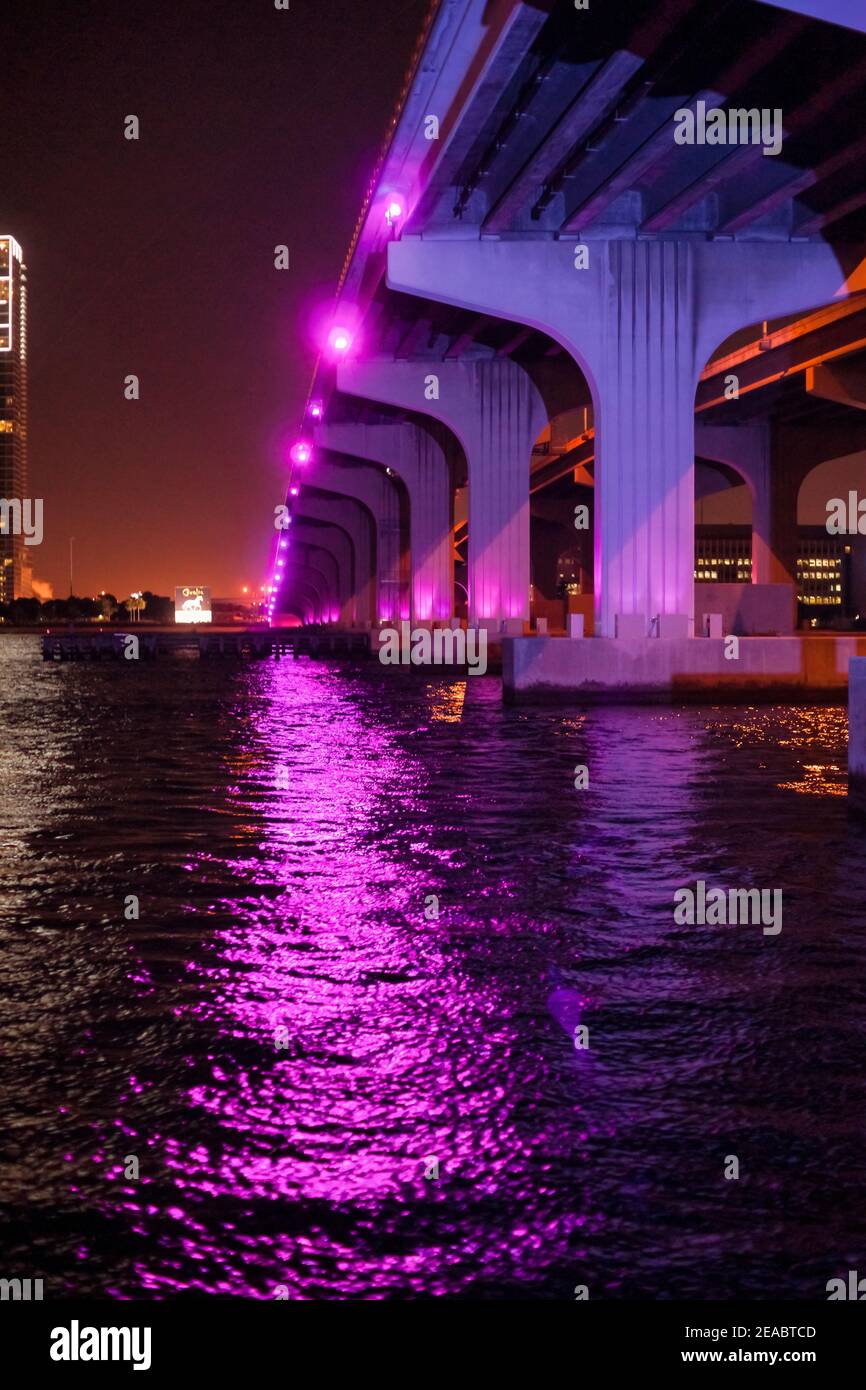 The substructure of the MacArthur Causeway Bridge lite at night with brightly colored magenta lights. Stock Photo