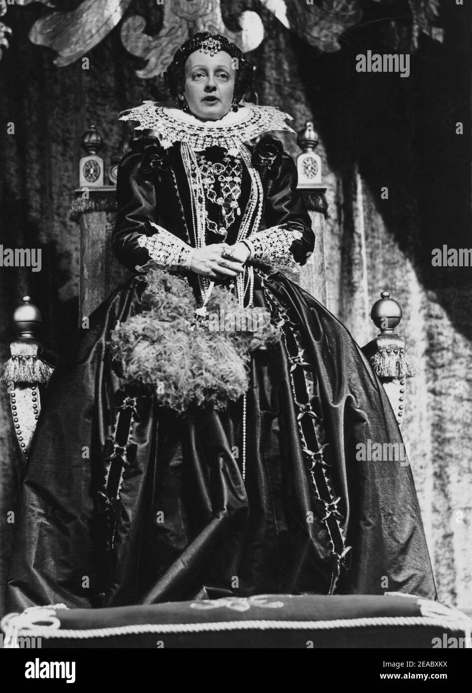 1939 , USA : The movie actress  BETTE  DAVIS ( 1908 -  1989 ) as the Queen of England Elizabeth I  in THE PRIVATE LIVES OF ELIZABETH AND ESSEX    ( Il conte di Essex  ) by  Michael Curtiz  , pubblicity photo Warner Bros by Bert Six  - CINEMA - FILM - attrice - portrait - ritratto - Regina Elisabetta I d' Inghilterra - collar - colletto - pizzo - lace - perle - perla - collana - ncklace pearls - pearl - raso - satin - trono - parrucca - wig - gioiello - gioielli - bijoux - jewellery - jewel - jewels  - ventaglio - fan - piume di struzzo - feathers  ----  Archivio GBB Stock Photo