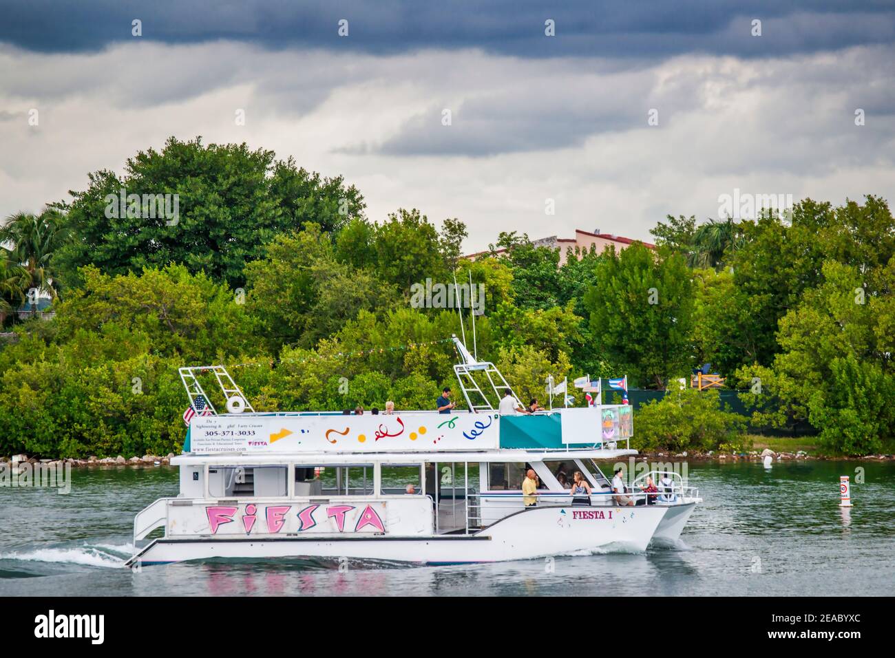 A tour boat passes by a Venetian Causeway island seen from a walkway at Jungle Island in Miami, Florida. Stock Photo