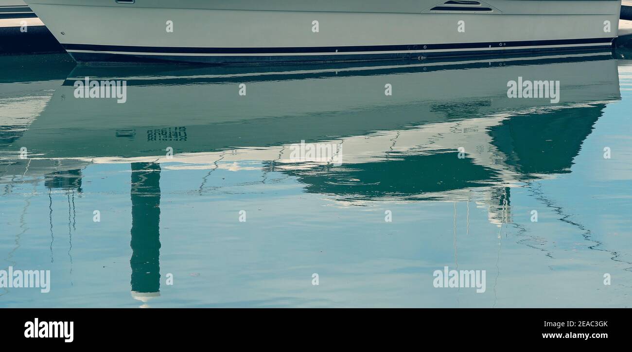 Close up of the sleek hull of a boat on the waterline reflected in the water Stock Photo