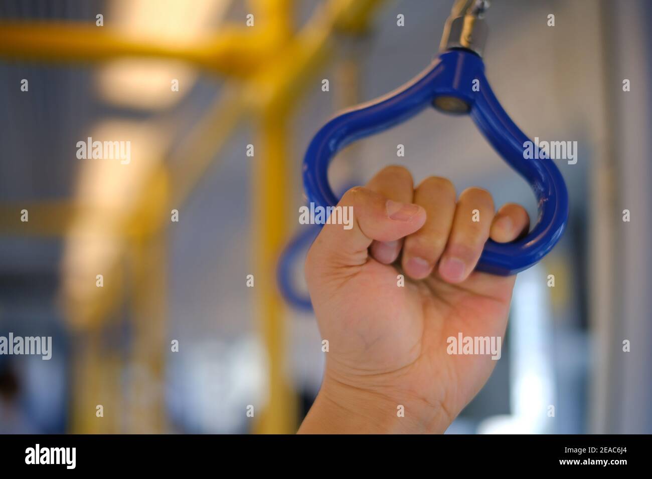 A hand grabbing a blue handgrip for stability on a sky train, traveling a highspeed. Stock Photo