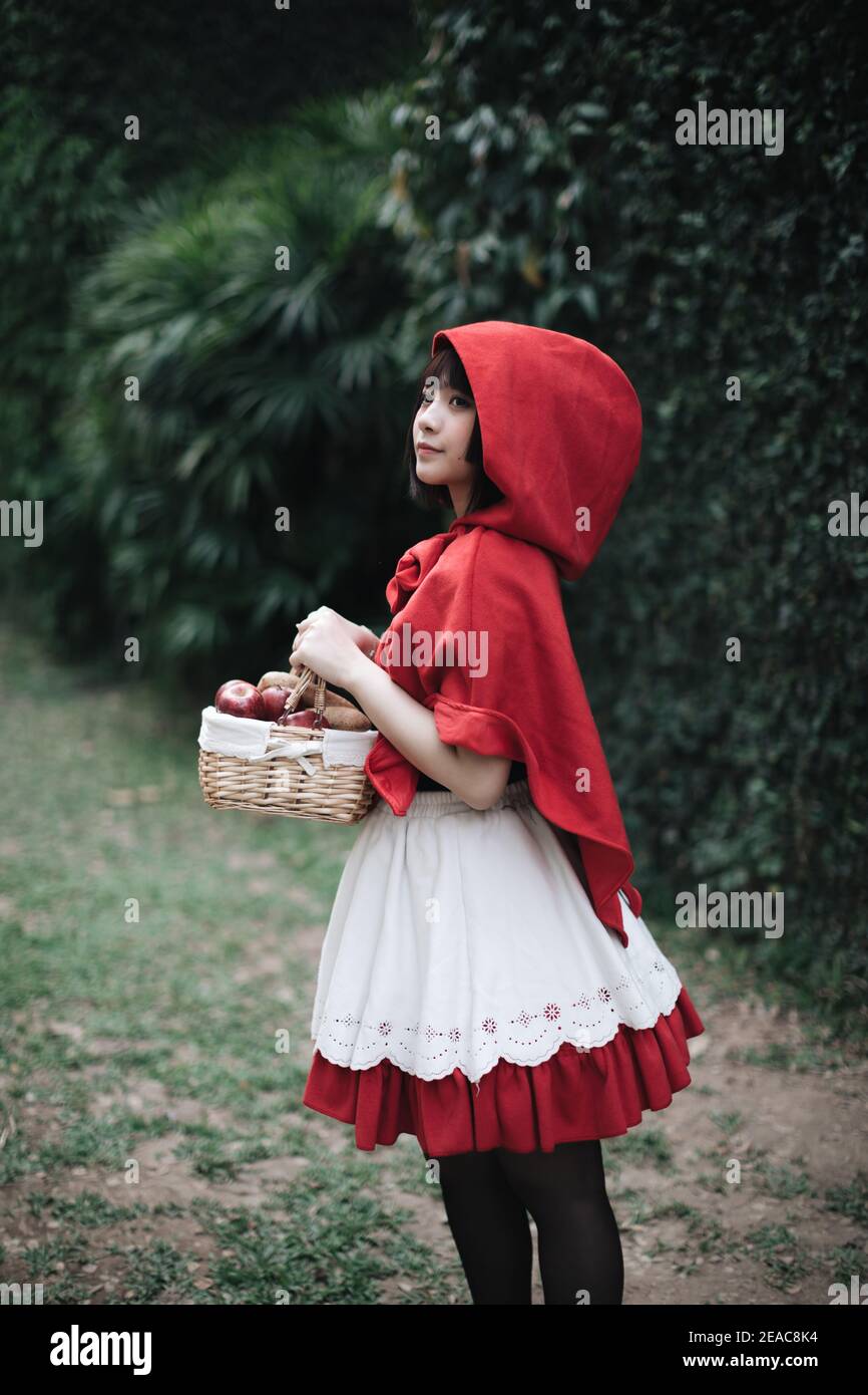 Portrait young woman with Little Red Riding Hood costume in green tree park  Stock Photo - Alamy