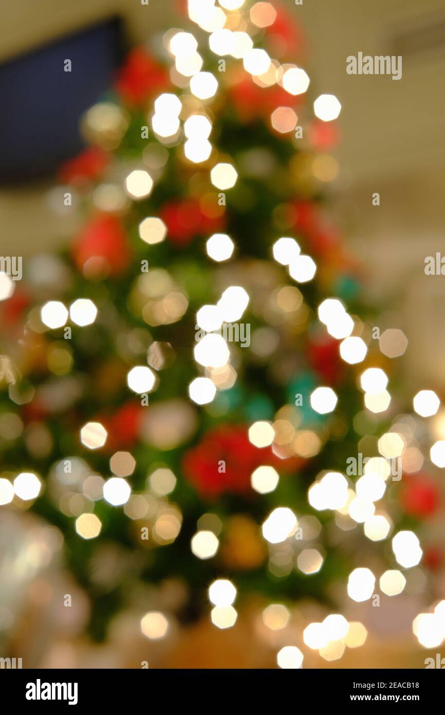 An out of focus picture of a Christmas tree, decorated with colorful ornaments and lights with beautiful round bokeh. Stock Photo