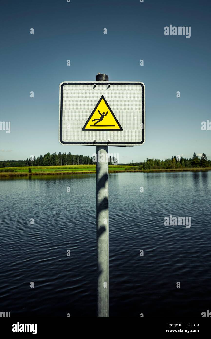 Beware of the danger of slipping sign on a swimming lake Stock Photo