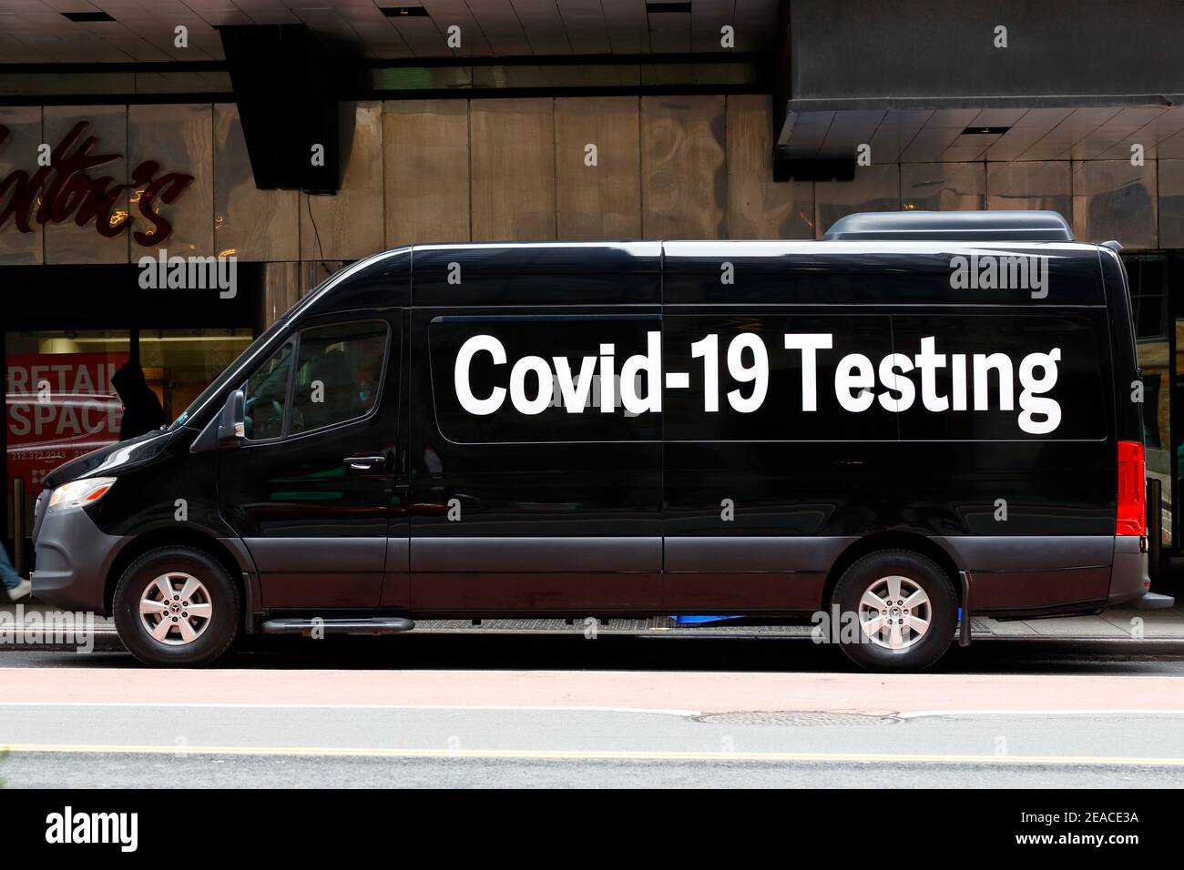 A black van with 'Covid-19 Testing' written in large font advertises itself as a pop-up coronavirus test site, New York, NY. Stock Photo