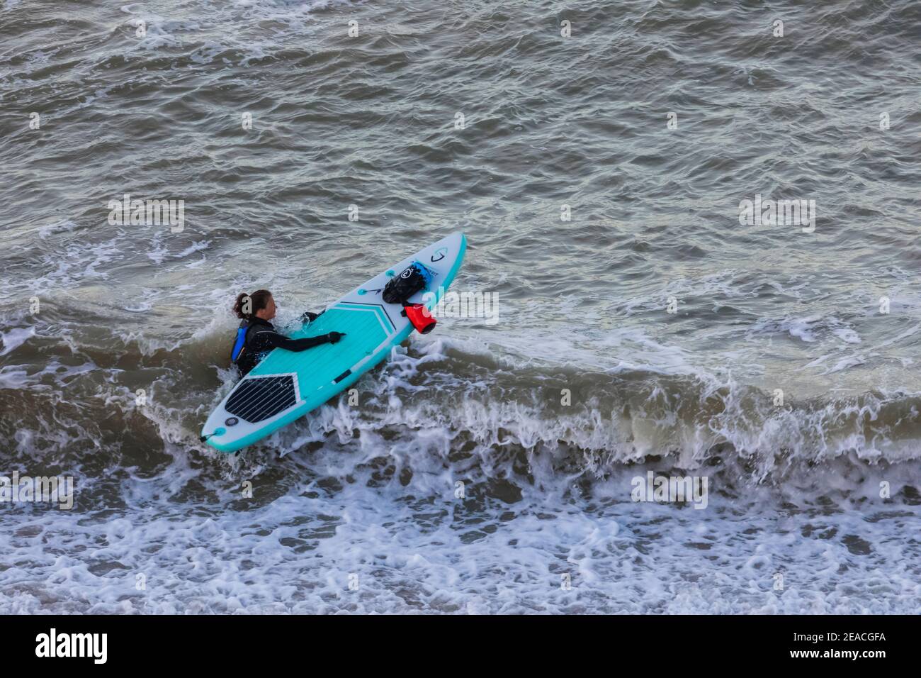 England, East Sussex, Eastbourne, Birling Gap, Paddle Boarder Entering the Water Stock Photo