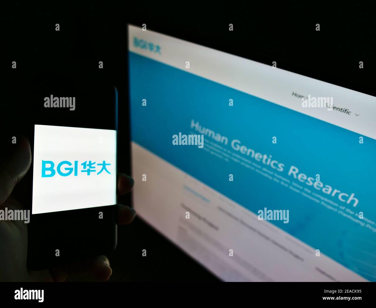 Person holding mobile phone with logo of Chinese genome sequencing company BGI Group on screen with business web page. Focus on cellphone display. Stock Photo
