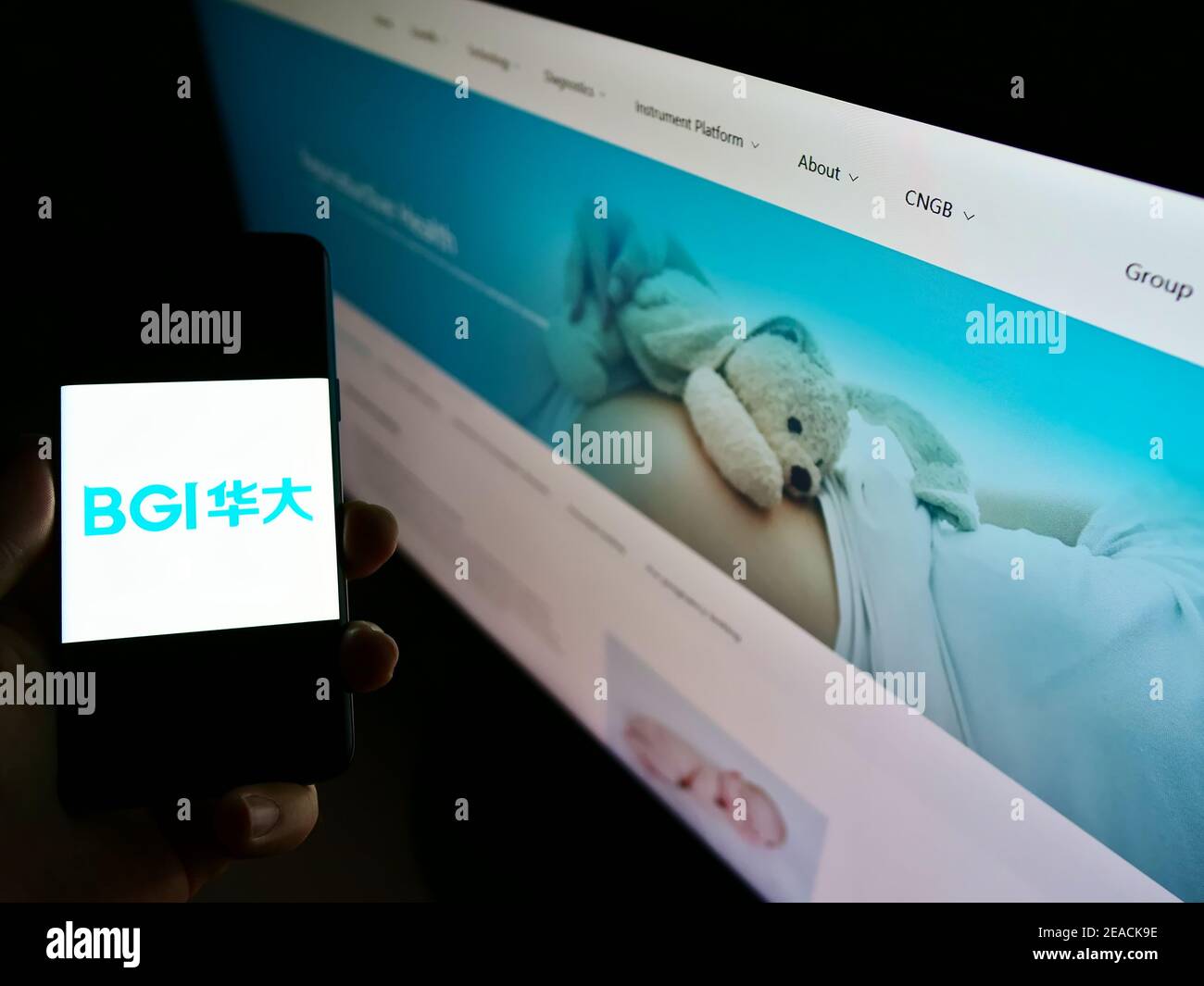 Person holding smartphone with logo of Chinese genetics company BGI Group on screen with business web page. Focus on mobile phone display. Stock Photo