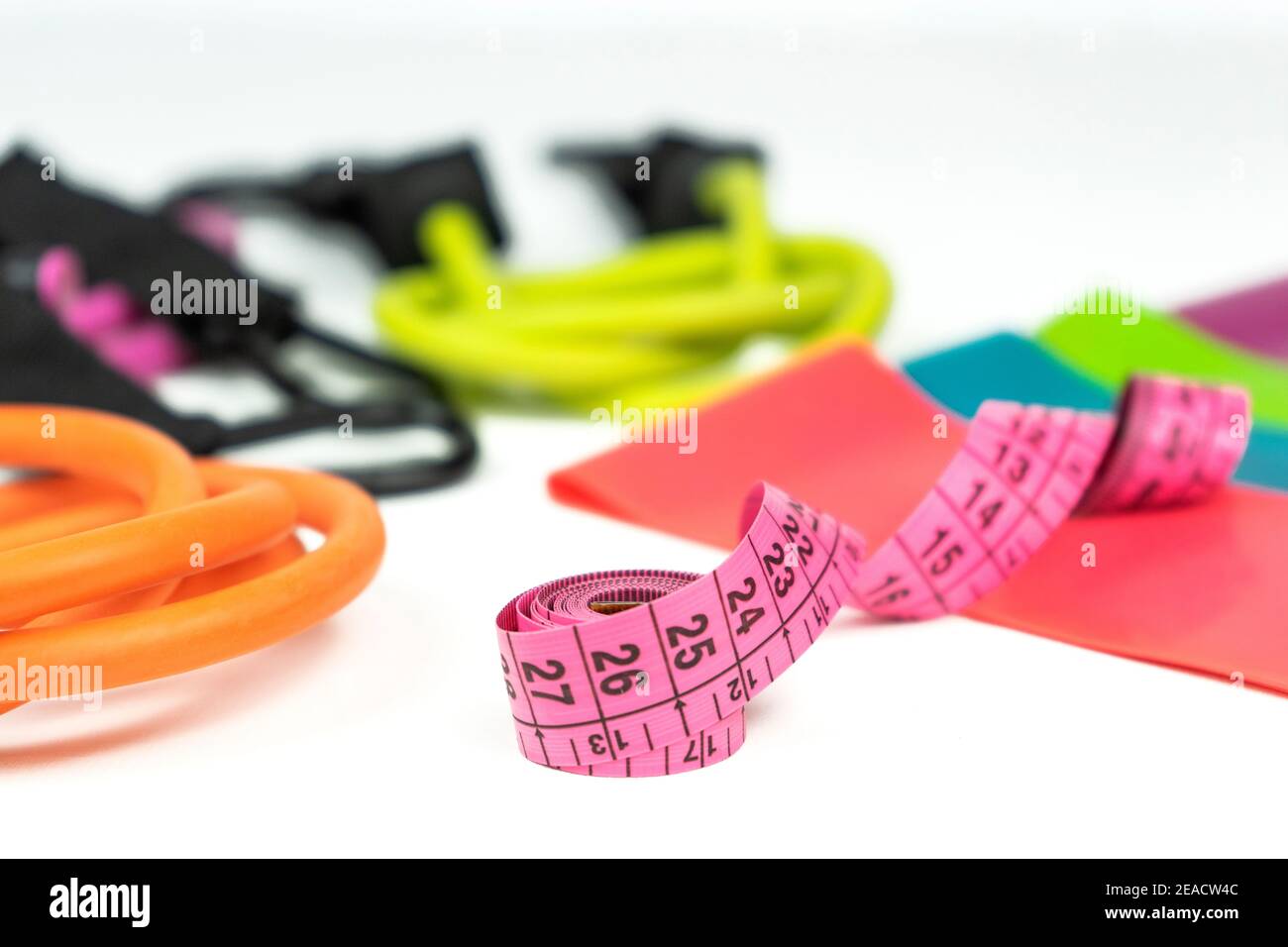 Colorful fitness elastic bands and expanders, a pink measuring tape lie on  a white floor Stock Photo - Alamy