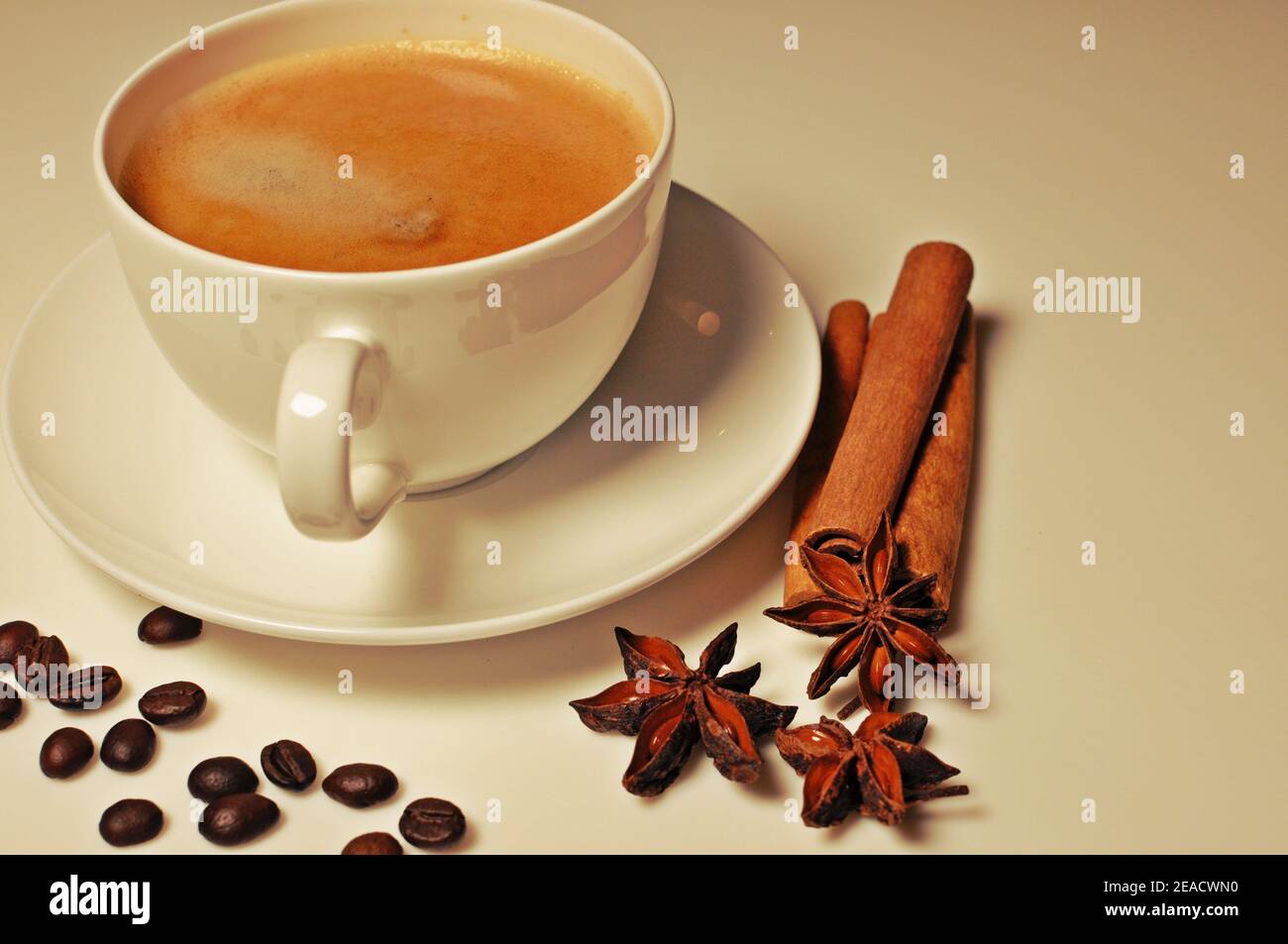 Cup of hot coffee with cinnamon, coffee beans and anise star decoration on white table background. Filter applied, side view Stock Photo