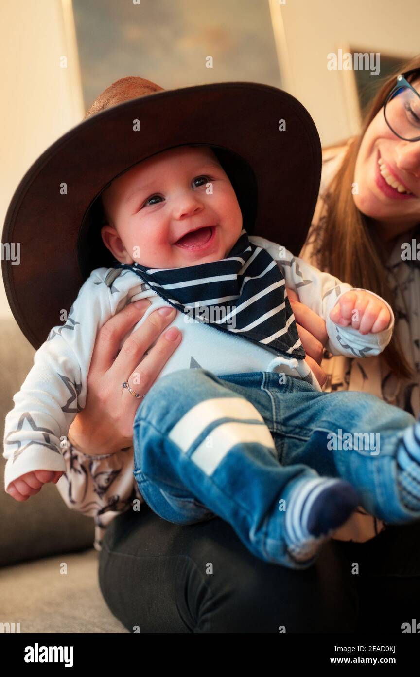 Portrait of cute little baby in cowboy hat holding by his mother Stock Photo