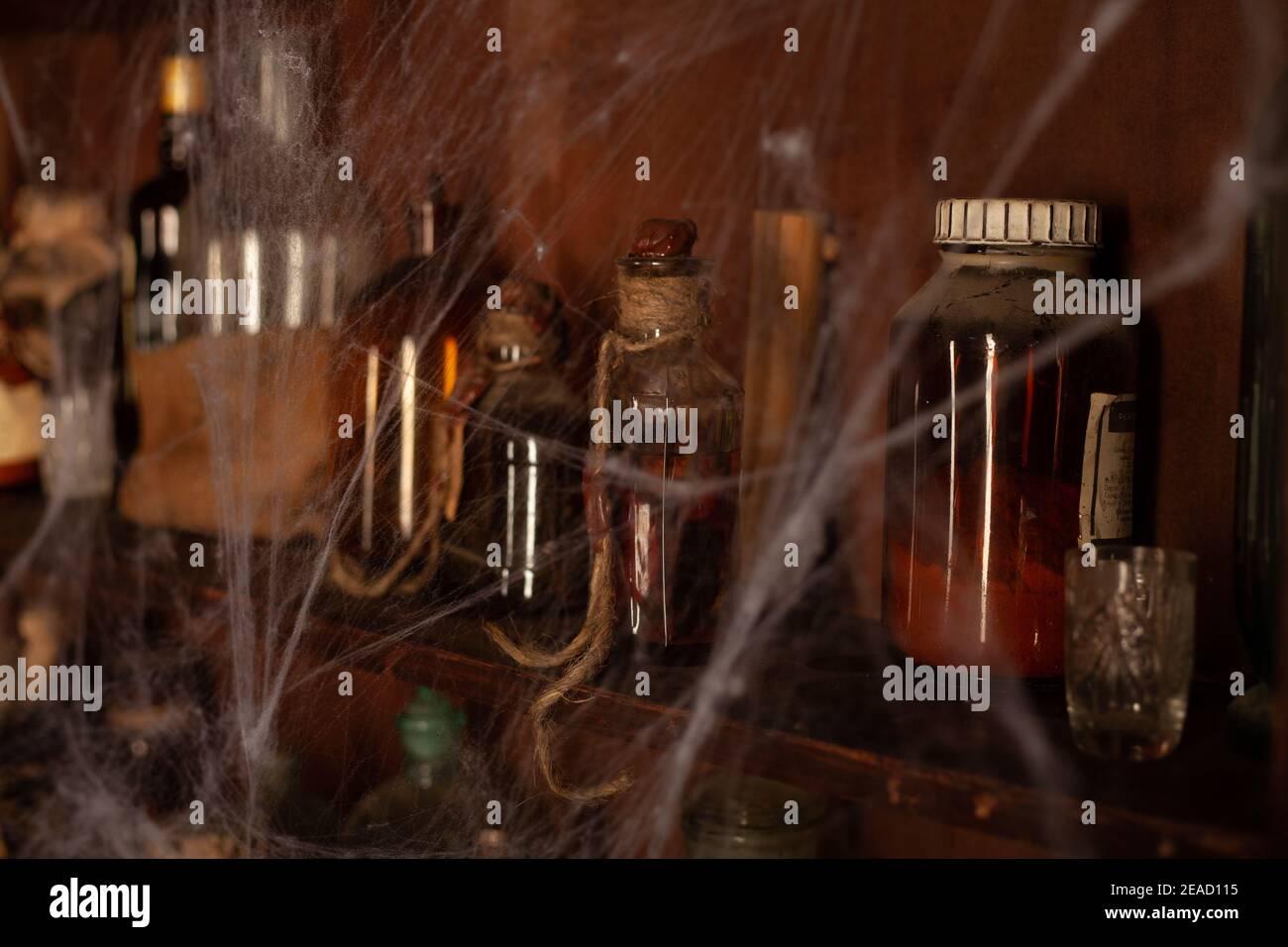 Halloween background Shelves with alchemy tools Skull spiderweb bottle with poison candles Witcher workspace Scarry room Stock Photo