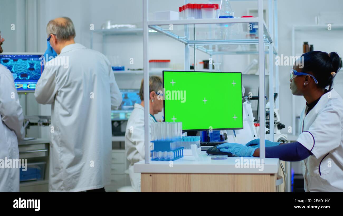 African scientist woman typing on computer with green mockup in modern ...