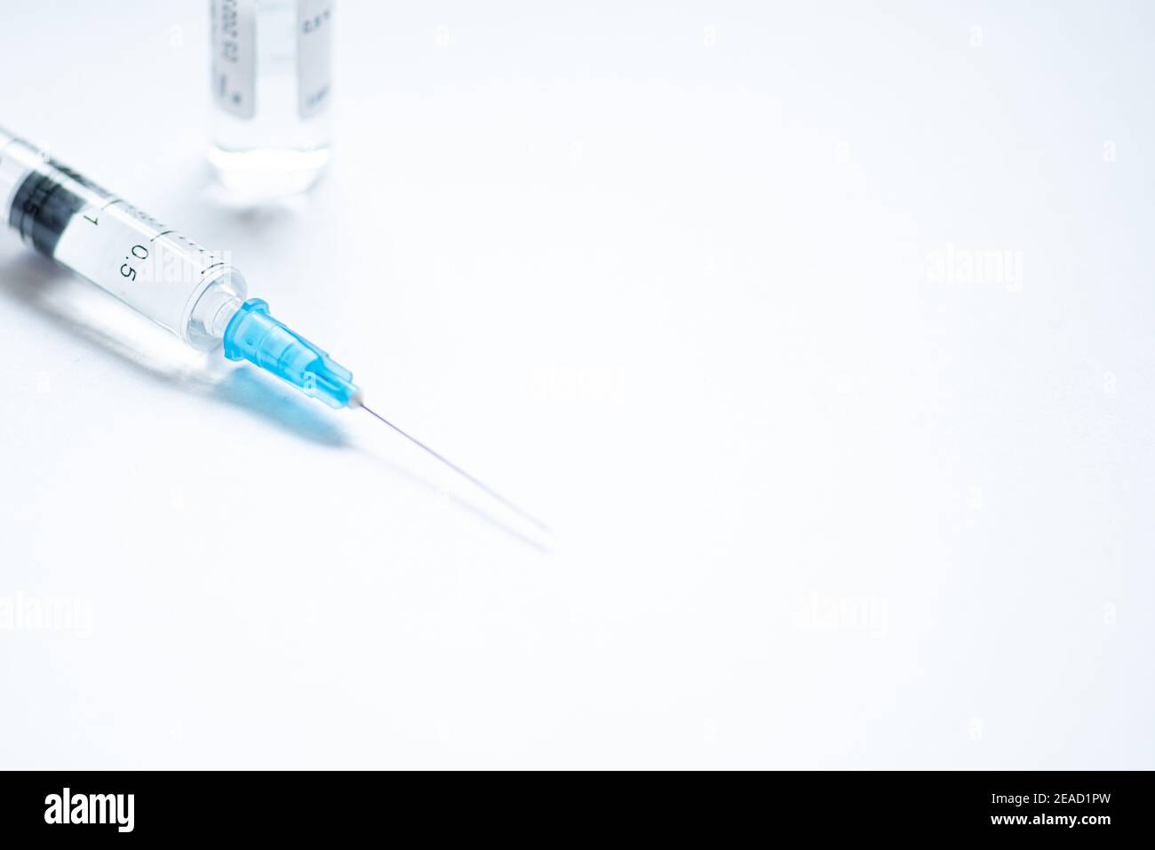 Syringe with needle without cover or top, vial or phial on a white empty space background ready to be used. Covid or Coronavirus vaccine or monoclonal Stock Photo