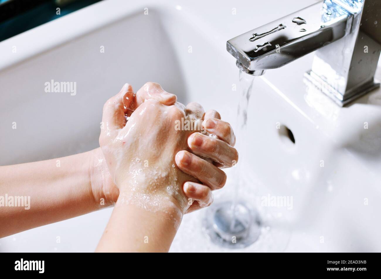 White European girl (child, kid) wash hands with soap over the sink Stock Photo