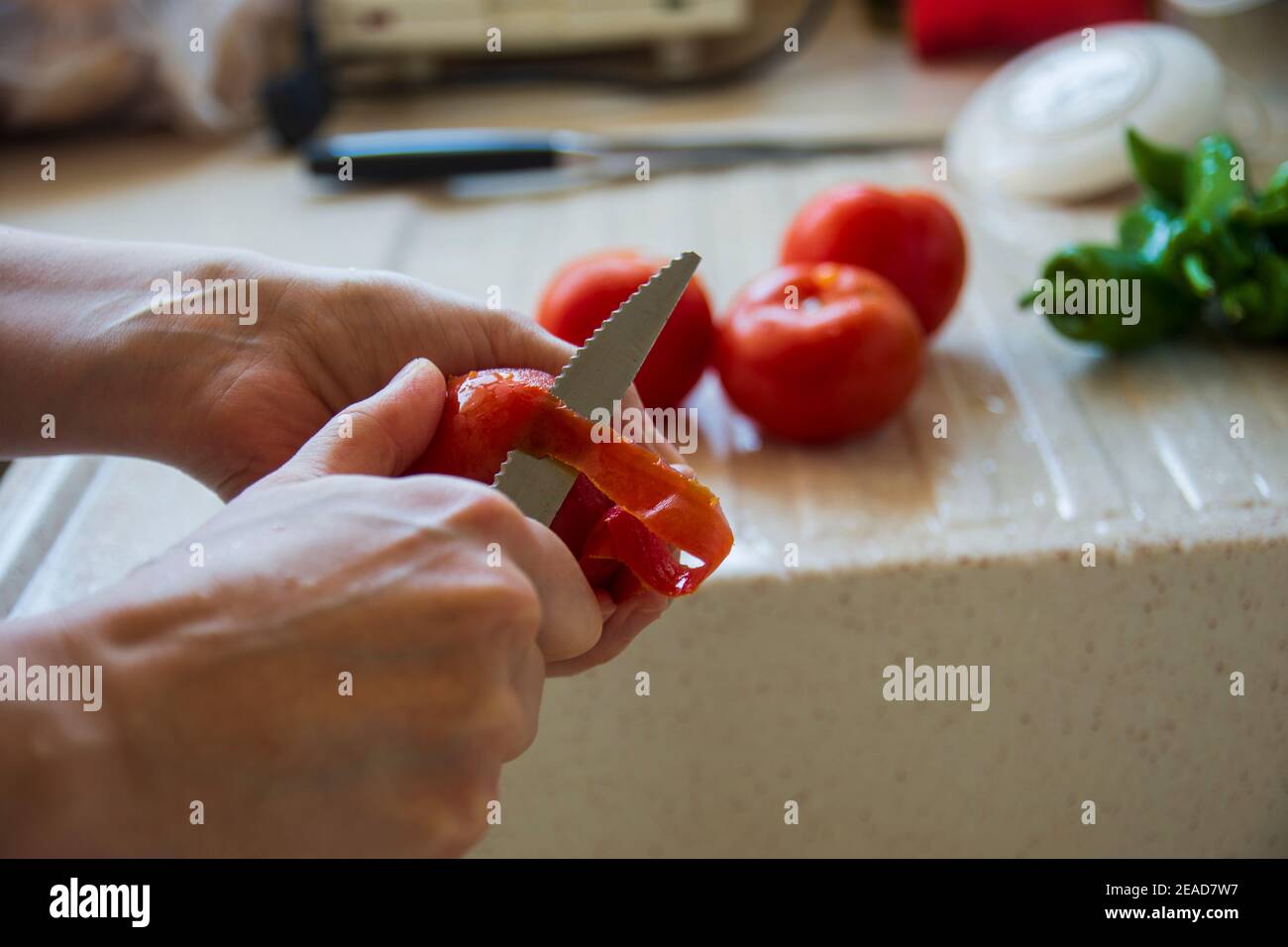 woman is peeling fresh tomato with knife. married woman is chopping fresh tomatoes and peppers. preparing a salad or meal Stock Photo
