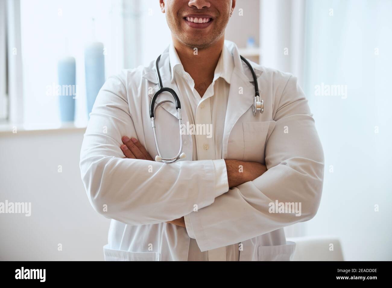 Handsome therapist with crossing arms in cabinet of medical center Stock Photo