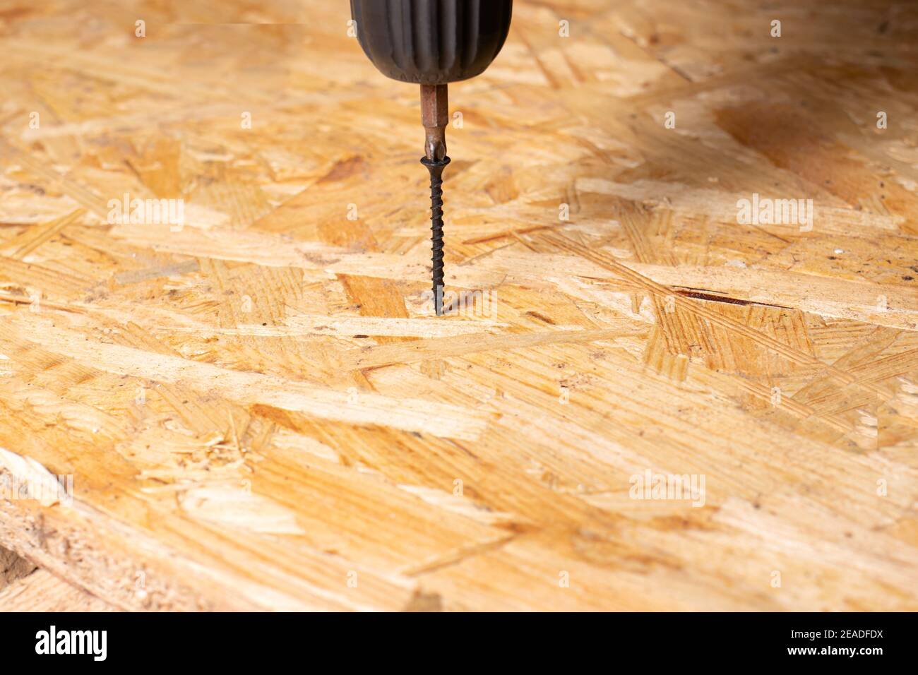 Screw and screwdriver on a chipboard sheet. Carpentry and construction tools with copyspace for text. Stock Photo
