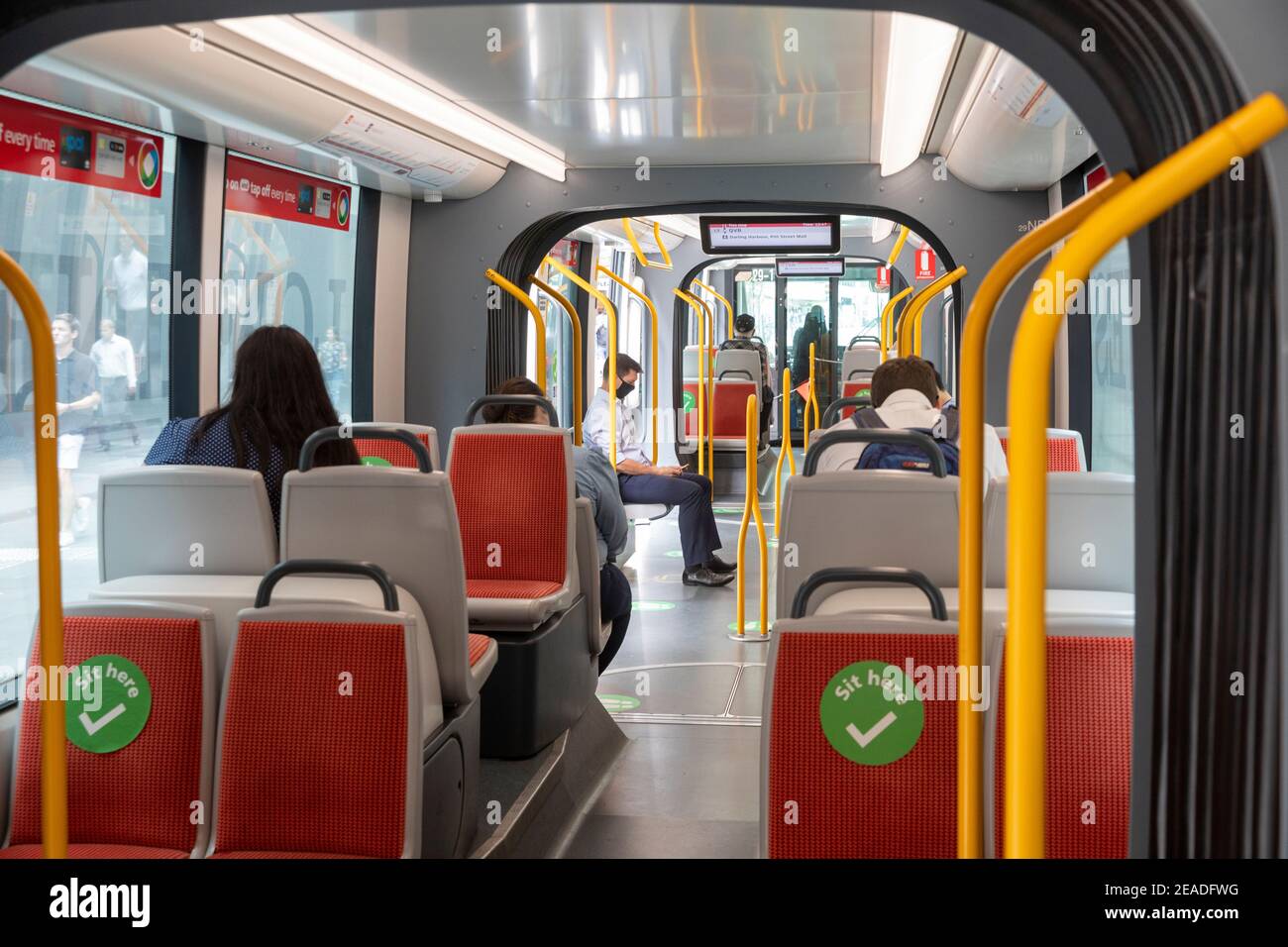 Sydney light rail train carriage interior, passengers commuting, sit here stickers act as social distancing during covid 19 pandemic,Sydney,Australia Stock Photo