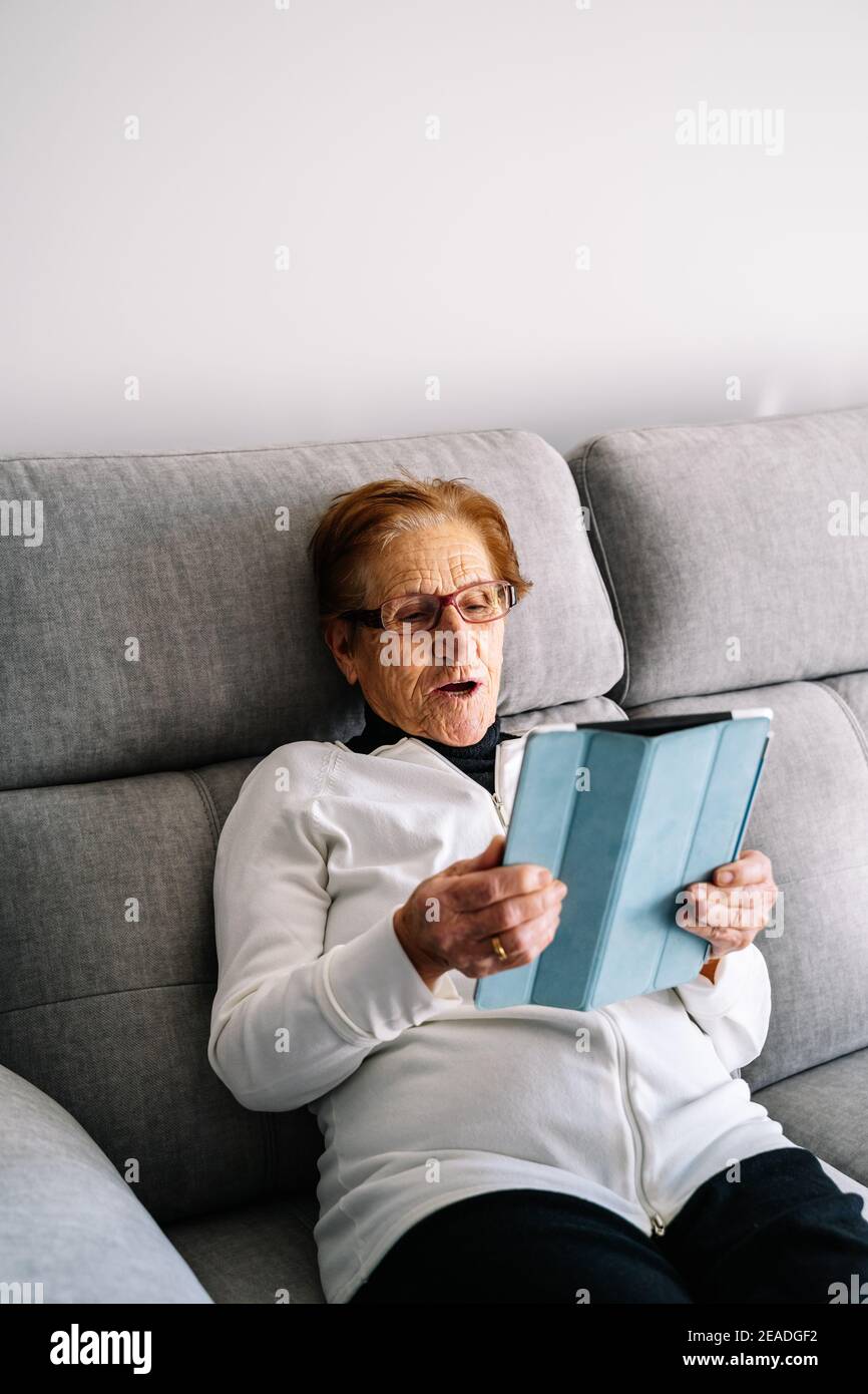 Old woman using a tablet to see and talk to her family during the covid confinement Stock Photo