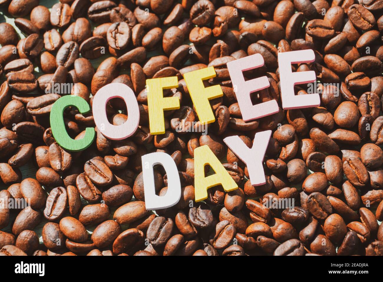 Coffee Day alphabets form on roasted coffee beans background. Stock Photo