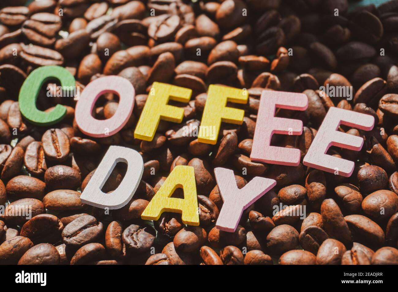 Coffee Day alphabets form on roasted coffee beans background. Stock Photo