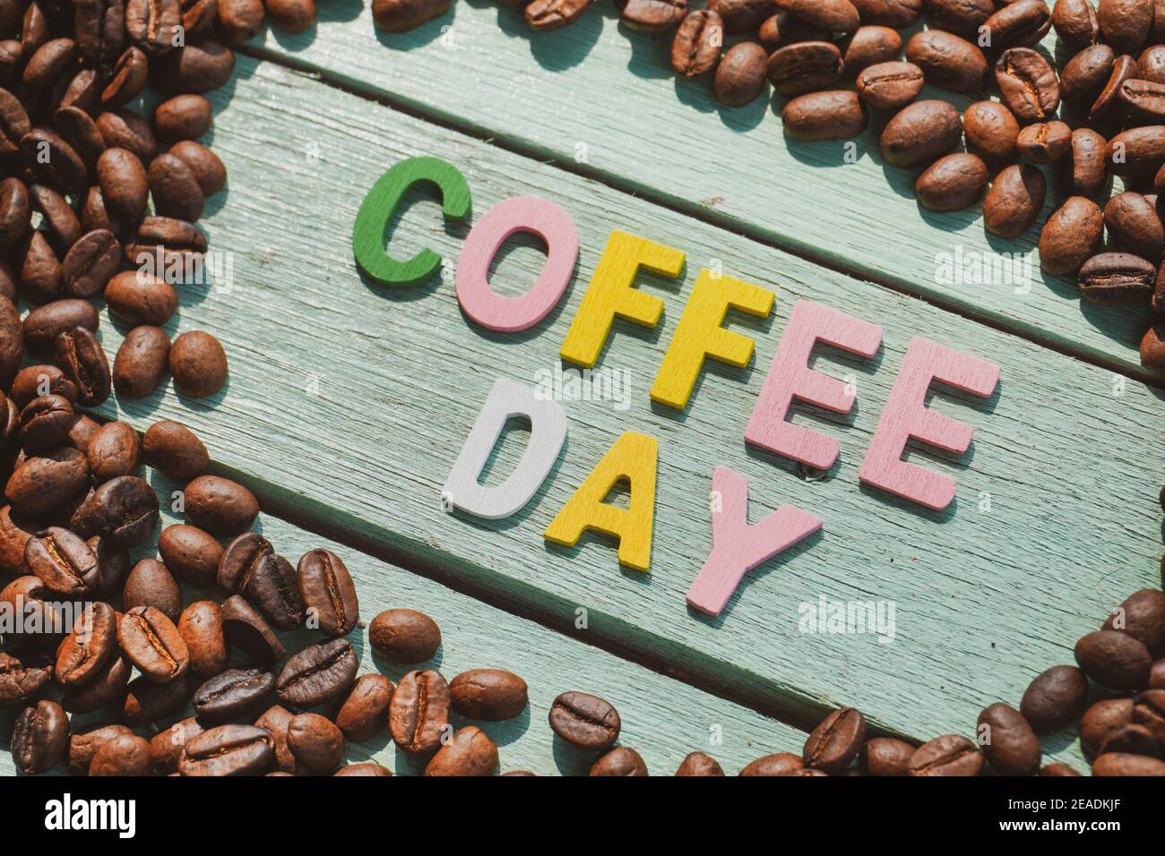 Coffee Day alphabets form on roasted coffee beans background. Stock Photo