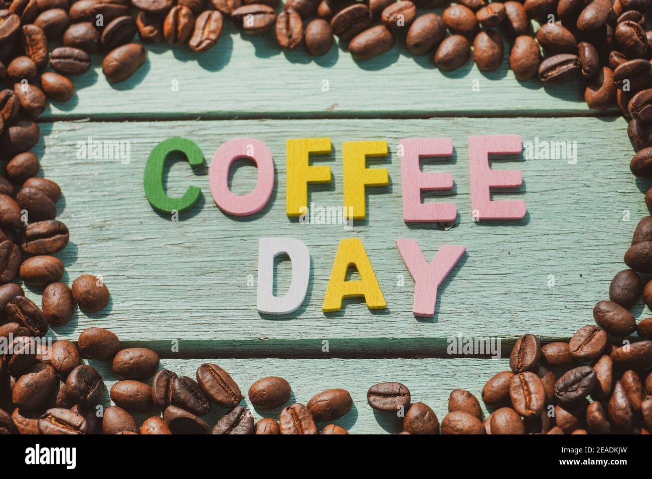 Coffee Day alphabets form on roasted coffee beans background. Stock Photo