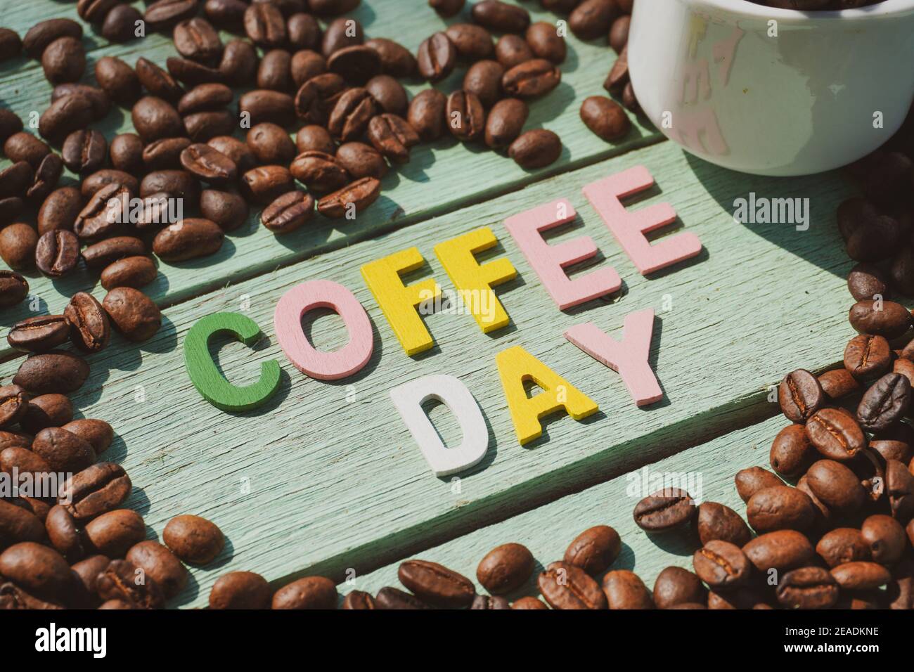 Coffee Day alphabets form on roasted coffee beans background. Stock Photo