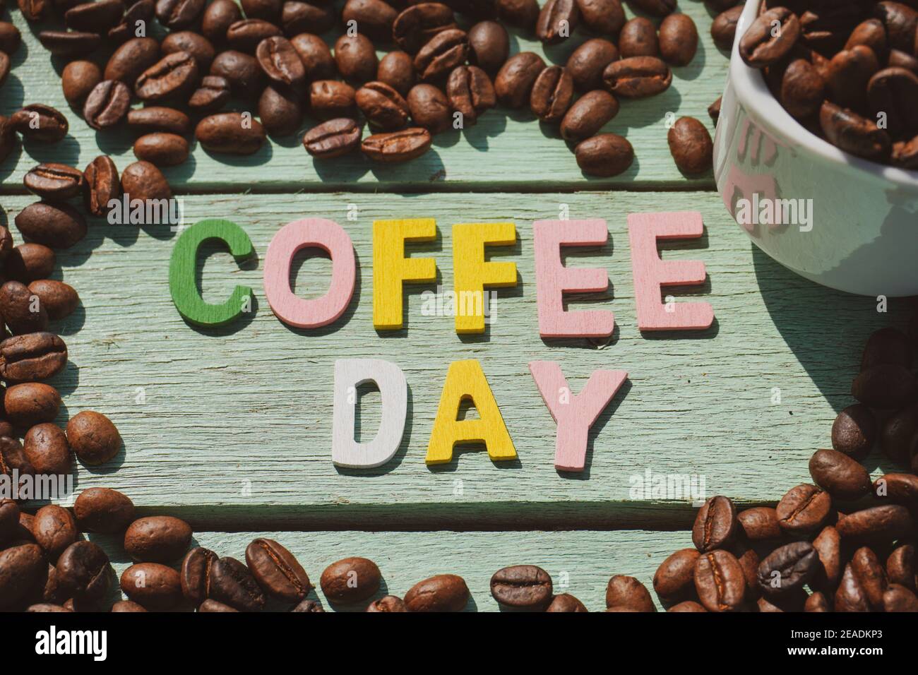 Coffee Day alphabets form on roasted coffee beans background. Stock Photo