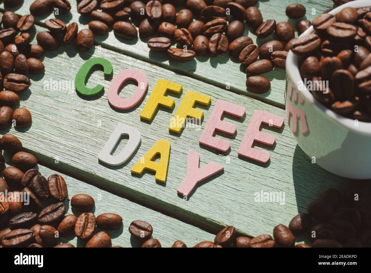 Coffee Day alphabets form on roasted coffee beans background. Stock Photo