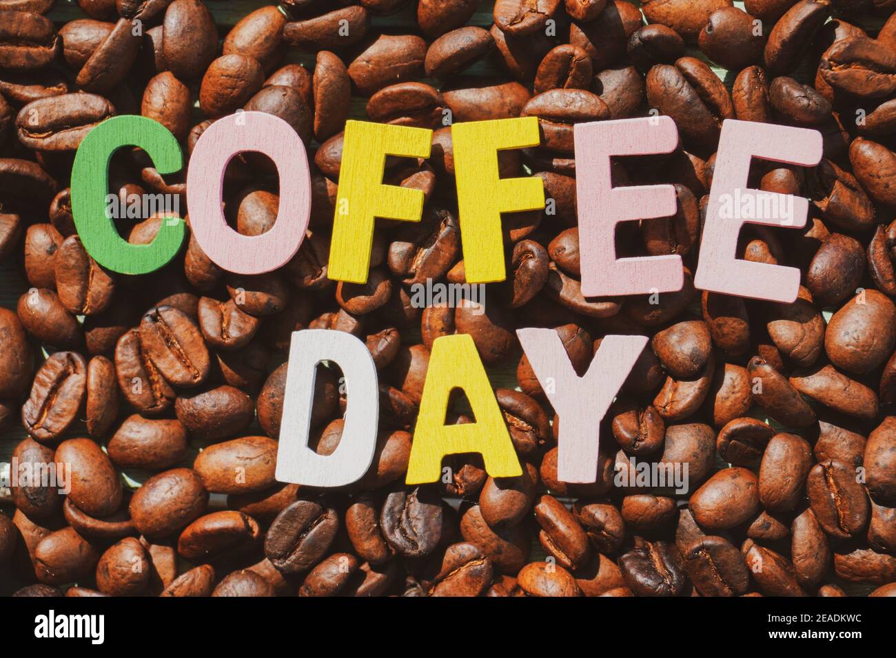 Coffee Day alphabets form on roasted coffee beans background. Stock Photo