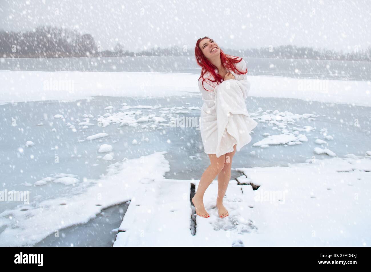 Happy woman hardening and winter swimming concept. Barefoot female enjoying cold snowy weather on an icy lake Stock Photo