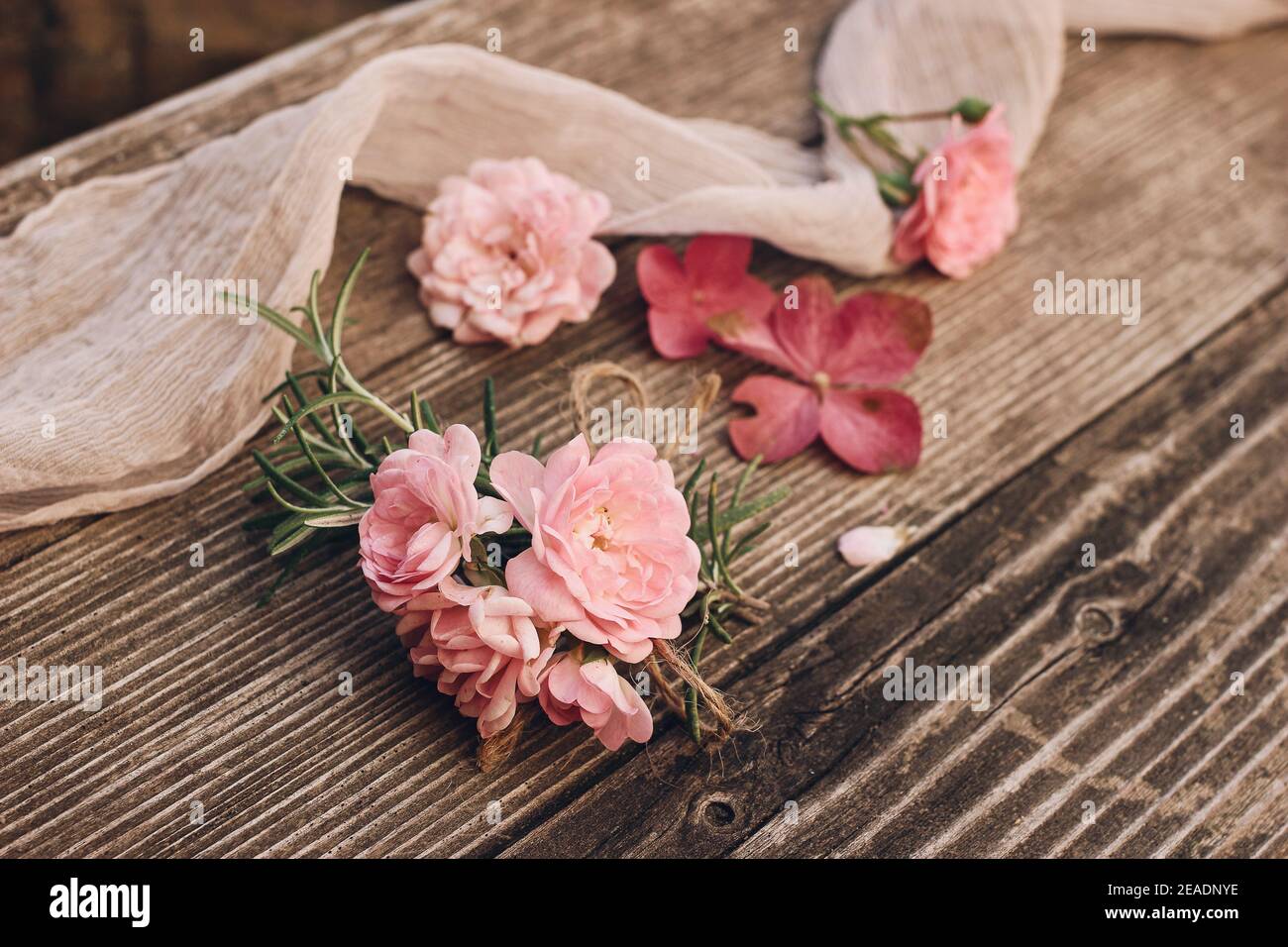 Summer feminine wedding styled stock photo. Floral composition with pink roses, hydrangea flowers and rosemary herb on old wooden table with silk Stock Photo