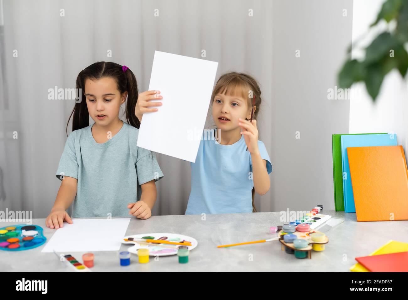 two little girls at the table with paints for drawing Stock Photo - Alamy