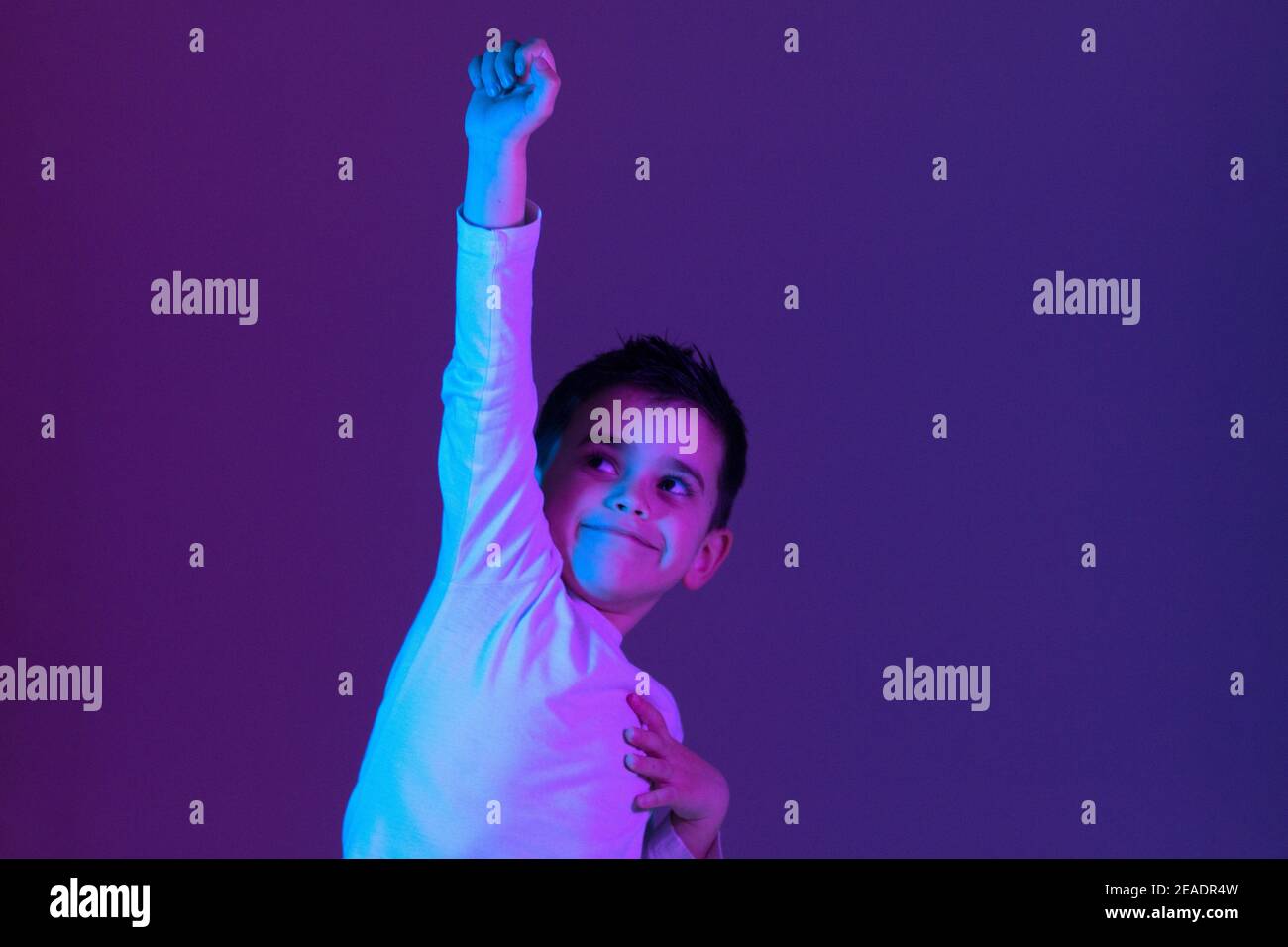 a boy making the victory gesture with his fist illuminated with neon lights. Winning concept Stock Photo