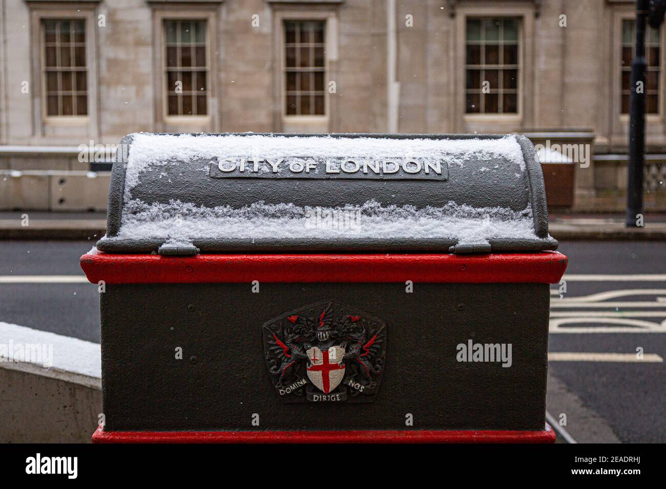 City of London bin in Central London during a snow day in winter. Red Bus at the background. Stock Photo